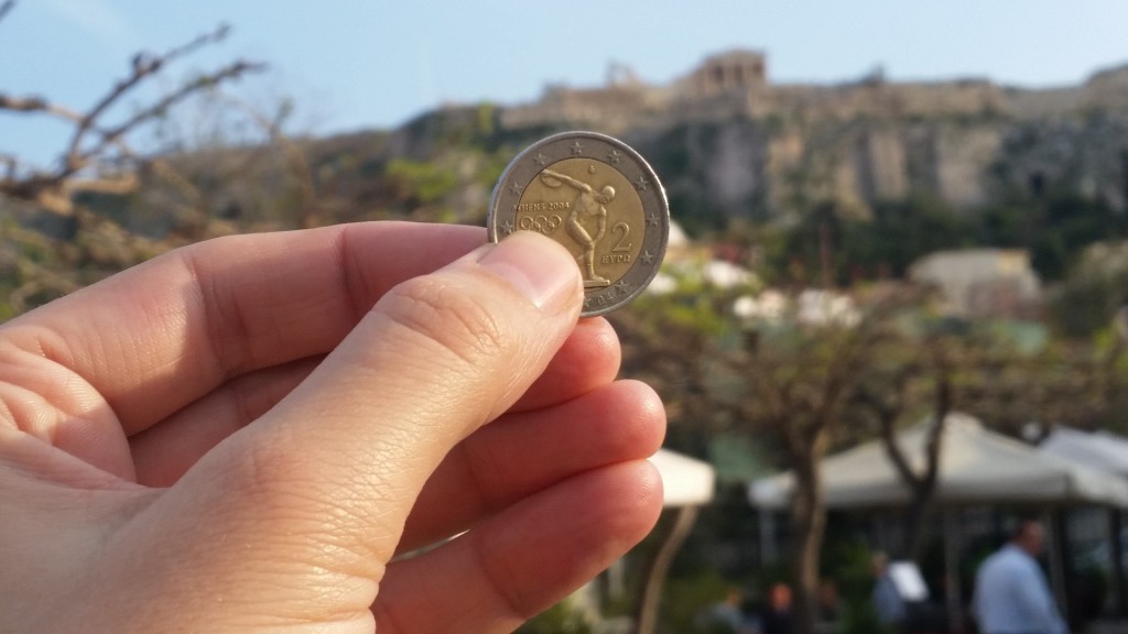 A Greek Euro coin foregrounds the Acropolis.